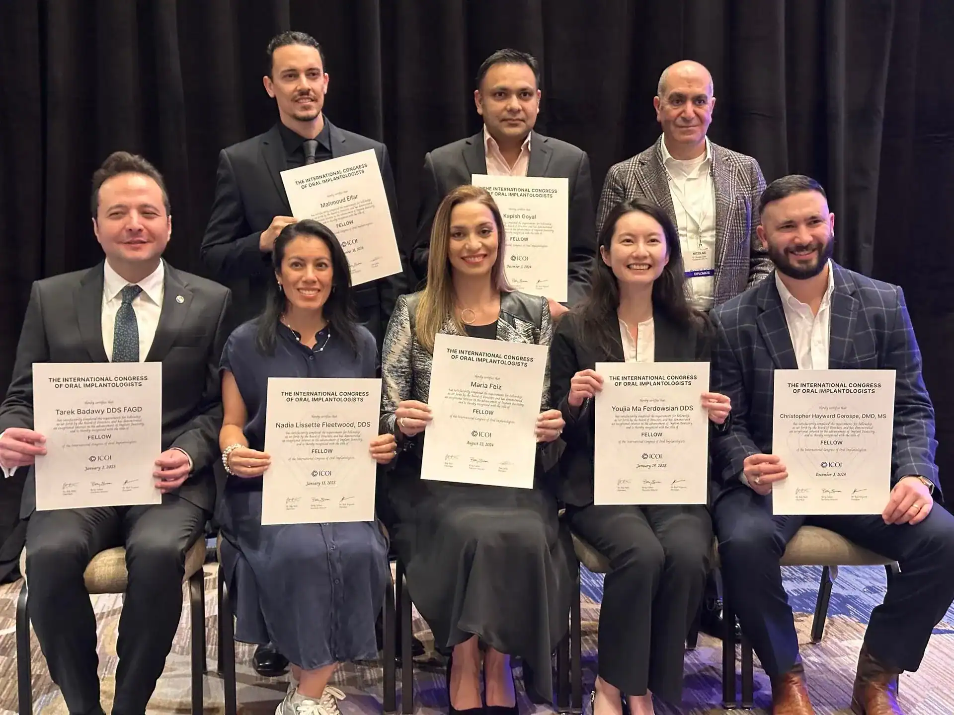 Dr. Tarek Badawy holding his Fellow certificate at an International Congress of Oral Implantologists ceremony.